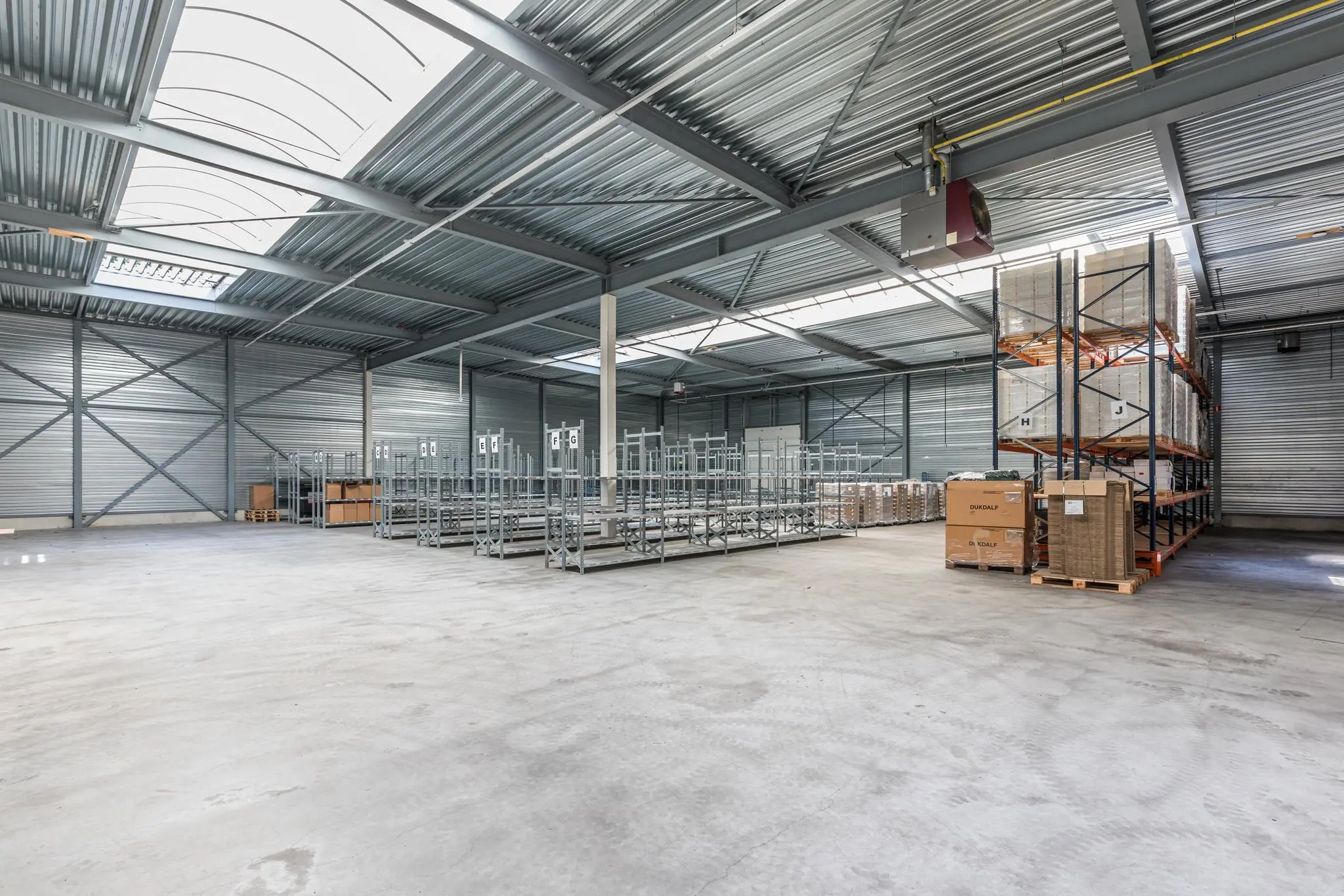 Ruime en moderne opslagloods aan de Laan Blussé van Oud-Alblas met metalen stellingen en opgeslagen pallets.